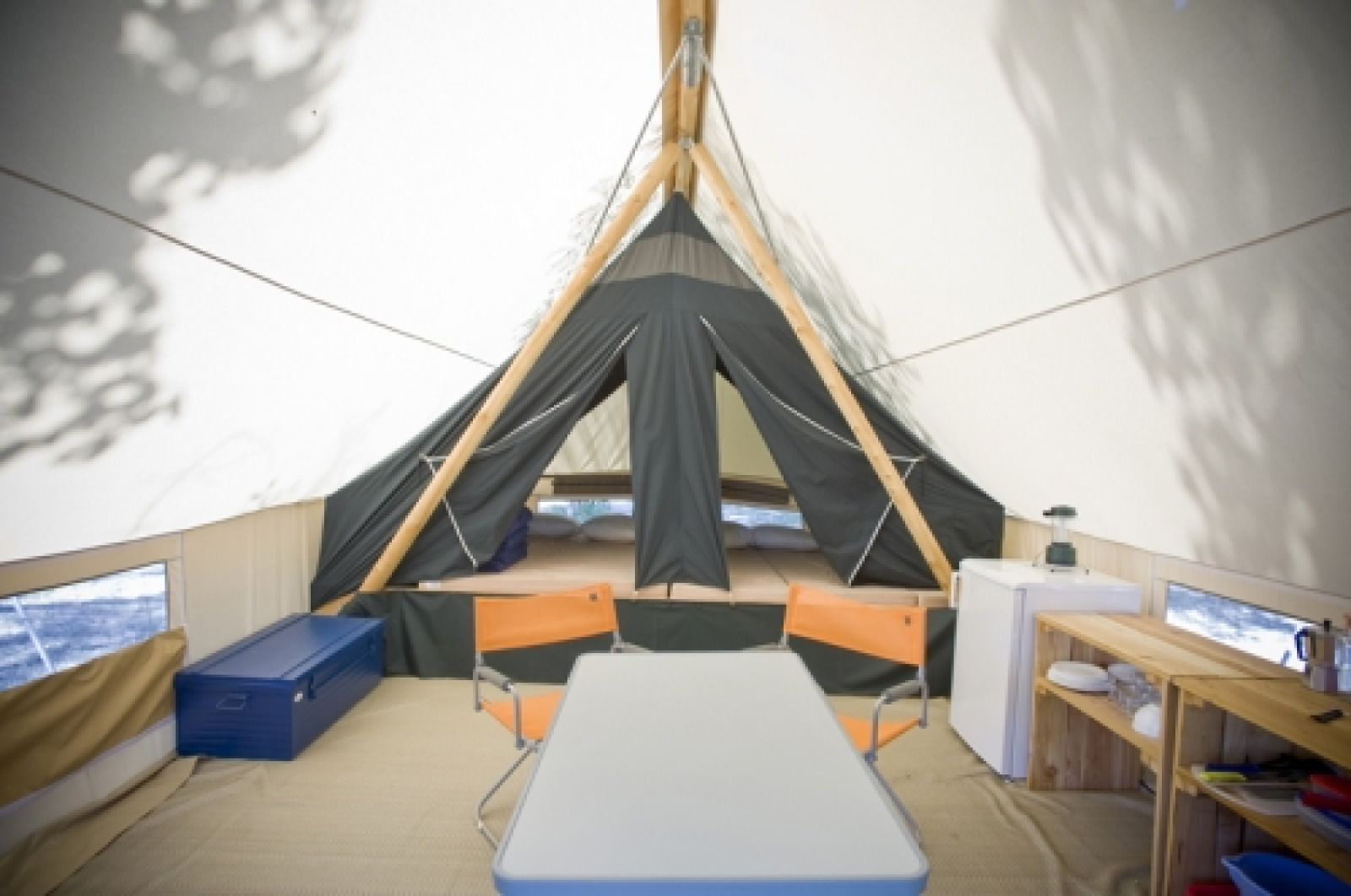 Interieur van een Canadienne safaritent bij Huttopia Rambouillet met tafel, stoelen en bed achterin.