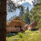 Træhytter ved Chalet Montana omgivet af skov og bjerge, fredelig naturferie i alperne om sommeren.