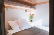Cama acogedora con sábanas blancas y flores en Chalet Montana de Huttopia Bozel en Vanoise, Francia.