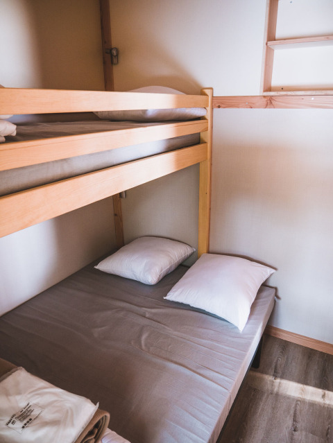 Foto de una litera en Chalet Montana, Huttopia Bozel en Vanoise, Francia, con dos almohadas y sábanas.