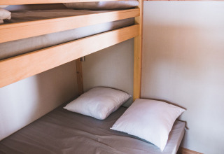 Foto de una litera en Chalet Montana, Huttopia Bozel en Vanoise, Francia, con dos almohadas y sábanas.