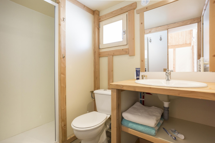 Baño luminoso con detalles de madera en Chalet Montana de Huttopia Bozel en Vanoise, Francia.