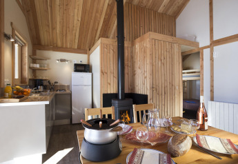 Indvendig udsigt af Chalet Montana-hytten på Huttopia Bozel en Vanoise med træinteriør og dækket spisebord.
