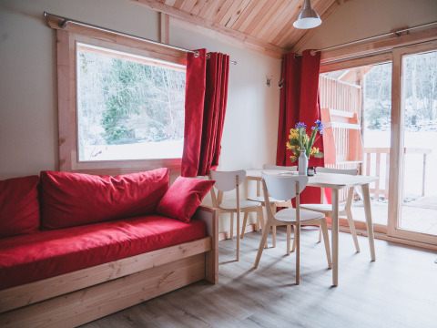 Hyggelig stue i Chalet Montana ved Huttopia Bozel en Vanoise, med røde gardiner og udsigt til sne.