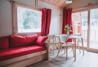 Hyggelig stue i Chalet Montana ved Huttopia Bozel en Vanoise, med røde gardiner og udsigt til sne.