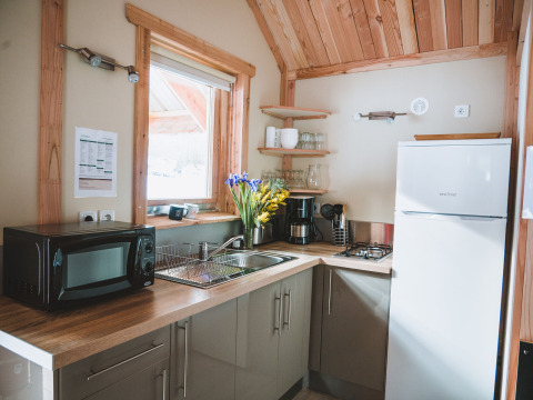 Moderne kabinekøkken i Chalet Montana, Huttopia Bozel en Vanoise, Frankrig med træpaneler og køkkenudstyr.