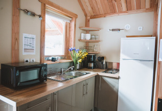 Moderne kabinekøkken i Chalet Montana, Huttopia Bozel en Vanoise, Frankrig med træpaneler og køkkenudstyr.