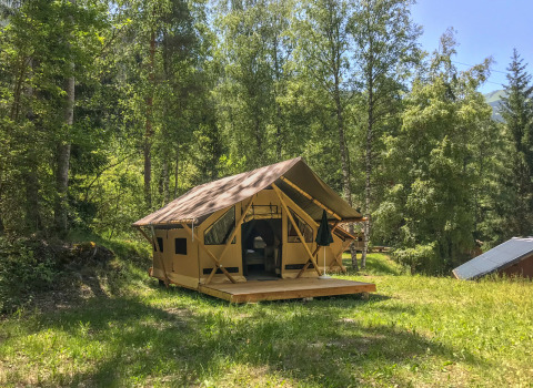 La tienda safari Canadienne-Tent en Huttopia Bozel en Vanoise, Francia, rodeada de frondosos árboles verdes.