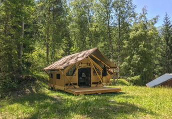 Das Safari-Zelt Canadienne-Tent im Huttopia Bozel en Vanoise in Frankreich, umgeben von grünen Bäumen.