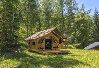 La tienda safari Canadienne-Tent en Huttopia Bozel en Vanoise, Francia, rodeada de frondosos árboles verdes.