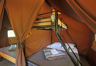 Interno della tenda Canadienne a Huttopia Bozel en Vanoise, Francia, con letti a castello e coperte.