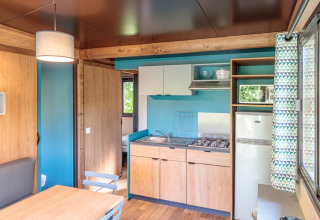 Moderne Küche und Essbereich im Chalet Evasion von Huttopia Landes Sud, Frankreich, mit viel Holz.