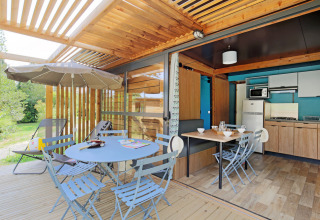 Chalet Evasion mit überdachter Terrasse, Essbereich und Küche bei Huttopia Landes Sud in Frankreich.