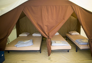 Binnenkant van een Bungalow tent Classic bij Huttopia Oléron les Pins in Frankrijk, met meerdere bedden.