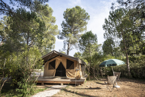 Safari telt Toile&Bois Sweet på Huttopia Fontvieille i Frankrig, omgivet af træer og natur.