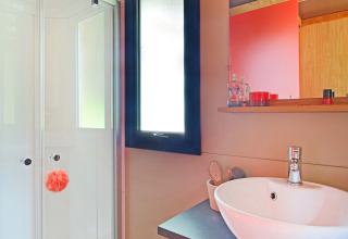 Modernes Badezimmer in einer Hütte, mit Duschkabine, Waschbecken, Holzunterschrank und Spiegel.