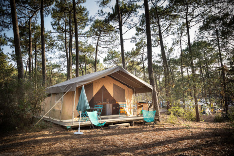 Tienda safari Toile&Bois Sweet en Huttopia Lac de Carcans, Francia, ubicada en un bosque de pinos.