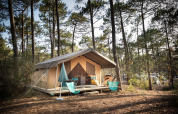 Tienda safari Toile&Bois Sweet en Huttopia Lac de Carcans, Francia, ubicada en un bosque de pinos.