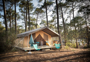 Tienda safari Toile&Bois Sweet en Huttopia Lac de Carcans, Francia, ubicada en un bosque de pinos.
