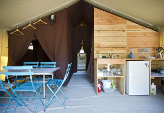 Interieur van een Toile&Bois safaritent met eetruimte en keuken bij Huttopia Lac de Carcans in Frankrijk.