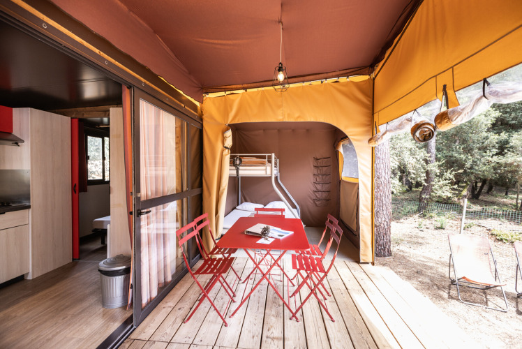 Safari-Zelt Arizona im Huttopia Lac de Carcans, Frankreich, mit rotem Esstisch und Naturblick.