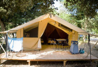 Tienda safari Toile&bois Classic con terraza de madera en la naturaleza, en Huttopia Noirmoutier, Francia.