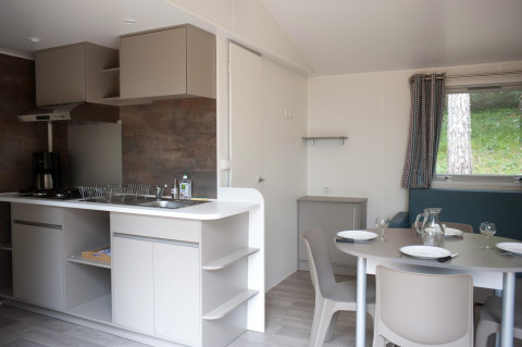 Cocina y comedor modernos en cabaña, con mesa puesta para cuatro y ventana grande con vista al exterior.