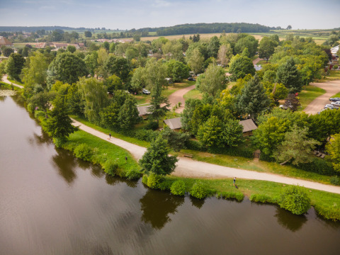 Vista aérea del parque vacacional Huttopia Etang de Fouché en Bourgogne-Franche-Comté, Francia junto a un lago.