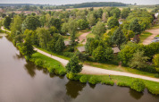 Vista aérea del parque vacacional Huttopia Etang de Fouché en Bourgogne-Franche-Comté, Francia junto a un lago.