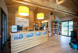 Reception area with wooden interiors at Huttopia Etang de Fouché holiday park in Bourgogne-Franche-Comté, France.