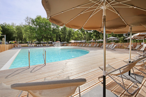 Piscina con tumbonas y sombrillas en el parque vacacional Huttopia Etang de Fouché, Borgoña, Francia.