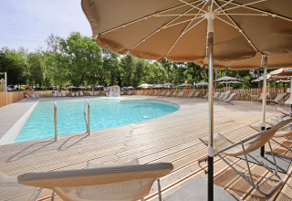 Swimmingpool med liggestole og parasoller i ferieparken Huttopia Etang de Fouché, Bourgogne, Frankrig.
