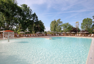 Udendørs swimmingpool med springvand og liggestole ved Huttopia Etang de Fouché feriepark i Bourgogne, Frankrig.