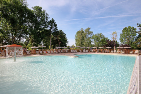 Udendørs swimmingpool med springvand og liggestole ved Huttopia Etang de Fouché feriepark i Bourgogne, Frankrig.