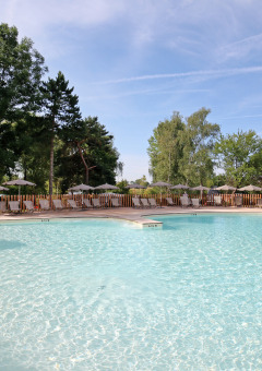 Piscina exterior con fuente y tumbonas en Huttopia Etang de Fouché, parque vacacional en Borgoña, Francia.