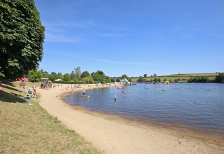 Strand med folk der bader og slapper af ved søen på Huttopia Etang de Fouché i Bourgogne, Frankrig.