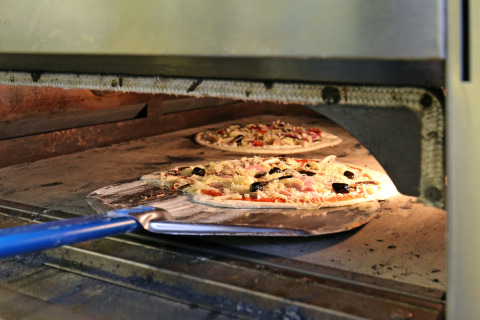 Pizza horneándose en horno de piedra en Huttopia Etang de Fouché en Bourgogne-Franche-Comté, Francia.