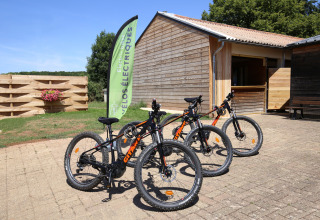 Vélos électriques à louer devant un chalet du parc Huttopia Etang de Fouché en Bourgogne, France.
