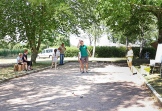 Vacanciers jouant à la pétanque sous les arbres au Huttopia Etang de Fouché en Bourgogne-Franche-Comté, France.