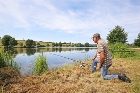Un hombre pescando junto al lago en Huttopia Etang de Fouché, rodeado de naturaleza en Borgoña-Franco Condado, Francia.