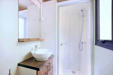 Baño moderno en Mobile home Vancouver con ducha, lavabo sobre encimera, espejo y ventana.
