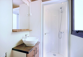 Baño moderno en Mobile home Vancouver con ducha, lavabo sobre encimera, espejo y ventana.