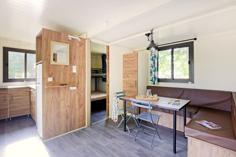 Lichte Mobile Home Vancouver glamping met keuken, zithoek en stapelbedden op de achtergrond.