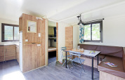 Glamping Mobile Home Vancouver luminosa con cucina, zona pranzo e letti a castello sullo sfondo.
