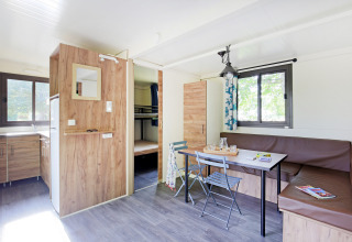 Helles Mobile Home Vancouver Glamping mit Küche, Essbereich, Eckbank und Etagenbetten im Hintergrund.