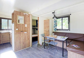 Glamping Mobile Home Vancouver luminosa con cucina, zona pranzo e letti a castello sullo sfondo.