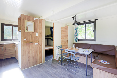 Helles Mobile Home Vancouver Glamping mit Küche, Essbereich, Eckbank und Etagenbetten im Hintergrund.