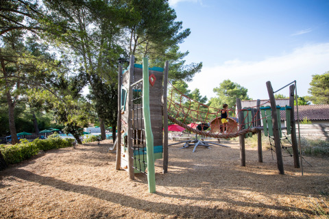 Parque infantil con redes para trepar y estructuras de madera en Huttopia Fontvieille, Provenza-Alpes-Costa Azul, Francia.