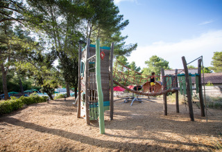 Speelplaats met klimnetten en houten structuren bij Huttopia Fontvieille, Provence-Alpes-Côte d’Azur, Frankrijk.
