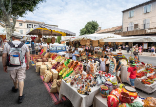 Mercato all'aperto vicino a Fontvieille, Provenza, con ceramiche colorate e cesti sui banchi del mercato.